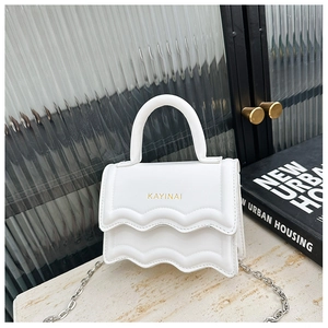 Close-up of white fashion handbag with wave-edge flap and metallic silver chain strap