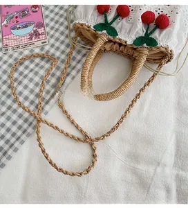 Detail of straw woven bag with white lace trim and red cherry embroidery decoration