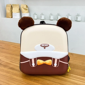 Dettaglio dello zaino a forma di orso con orecchie di peluche e guscio rigido su legno
