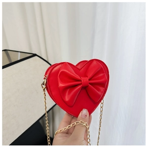 Détail du sac rouge en forme de cœur pour fille avec gros nœud et chaîne dorée