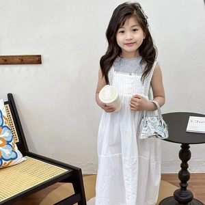 Fillette portant une robe blanche sans manches en coton avec dentelle et volants délicats