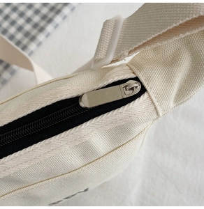 Détail du sac en toile crème avec fermeture éclair métallique et sangle réglable
