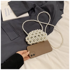 Detail of handmade white pearl woven mini bag with long beaded shoulder strap on a grey blazer