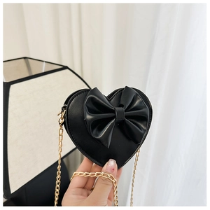 Détail d'un sac cœur pour fille avec grand nœud et bandoulière en chaîne dorée