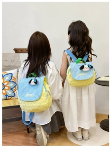 Detail of yellow quilted children backpack with blue checkered flap and dog charm