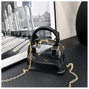 Detail of a mini shell-shaped crossbody bag with black leather and transparent PVC textures