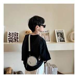 Detail view of mini round silver crossbody bag with COOL print on adjustable strap