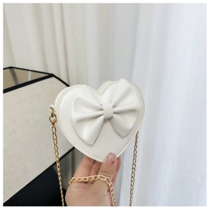 Détail du sac bandoulière enfant en forme de cœur blanc avec nœud et chaîne dorée