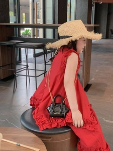 Close-up of a child wearing a red ruffled dress with a black patent leather chain bag