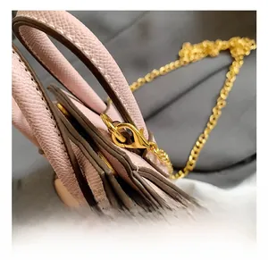Détail macro du sac en cuir Saffiano rose avec mousqueton doré et chaîne en métal