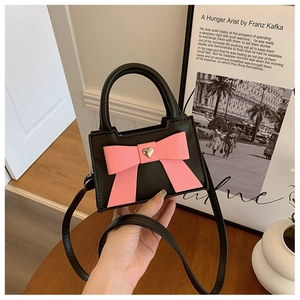 Détail d'un mini sac bandoulière avec un nœud rose et un ornement en métal cœur doré