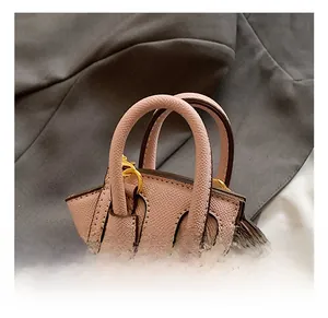 Gros plan détaillé d'un mini sac rose texturé avec des anneaux dorés et doubles poignées