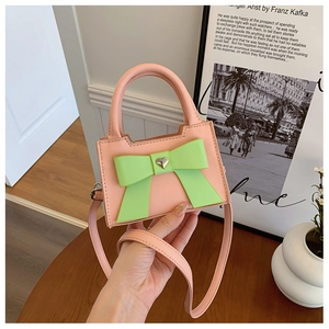 Détail du mini sac rose orné d'un grand nœud vert et d'une boucle coeur doré
