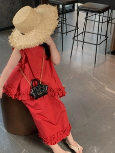 Red sleeveless ruffle dress styled with a straw hat and black patent chain bag