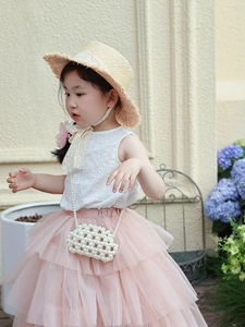 Detail of girls floral outfit featuring white lace top and pink tulle skirt with pearl bag
