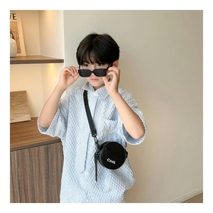 Detail of round black crossbody bag for boys with white COOL print and matching sunglasses