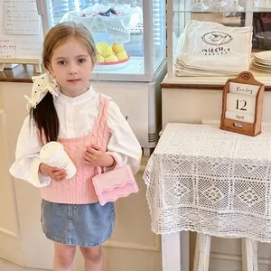 Pink knit vest with white shirt and blue denim skirt for girls in a cafe setting
