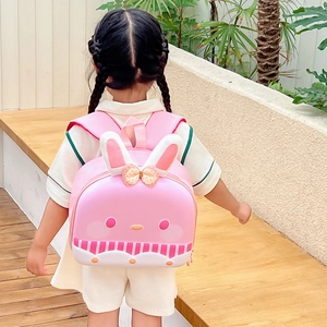 Pink cartoon rabbit shell backpack for girls shown on a child model in an outdoor setting
