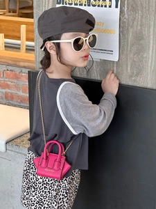 Détail d'un mini sac en cuir rose avec chaîne dorée et forme aile porté par un mannequin
