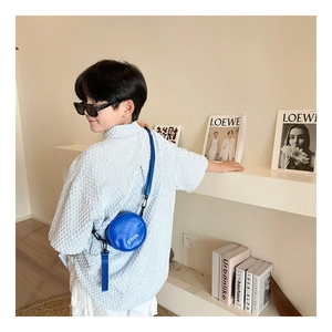 Detail of round mini crossbody bag for boys in bright blue with COOL lettering
