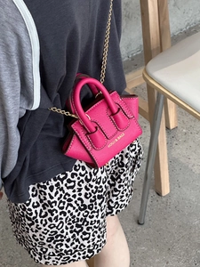 Détail du mini sac bandoulière rose rouge avec chaîne dorée et finition cuir texturé