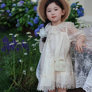 Robe de fille en tulle brodé avec mini sac en perles dans un décor de jardin