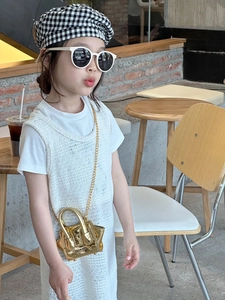 Close-up of golden metallic mini crossbody bag with chain strap on a little girl