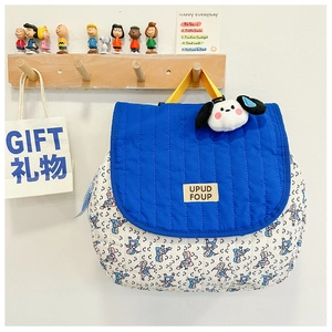 Detail of quilted kids backpack featuring cartoon print and cute puppy plush pendant