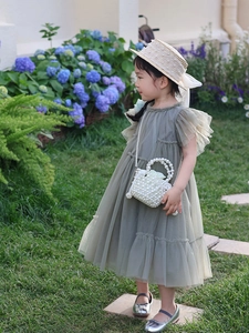 Détail de robe en tulle gris pour fille avec panier en perles et chapeau de paille