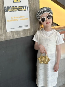 Detail of a girl wearing a white knit vest dress with a chic gold metallic mini handbag