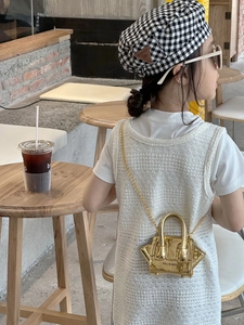 Close-up of golden star-shaped mirror mini bag with metallic chain on kids stylish outfit