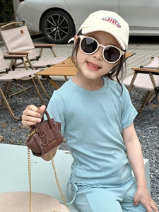 Détail d'un mini sac bandoulière en cuir marron avec chaîne dorée et coutures blanches
