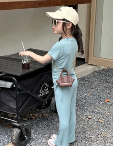 Bébé en ensemble côtelé bleu avec un mini sac à chaîne en cuir marron à l'extérieur