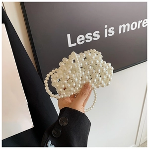 Detail of white handmade pearl woven mini handbag with circular handle held by model