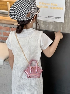 Rear view of a child wearing a pink holographic wing-shaped crossbody bag with gold chain