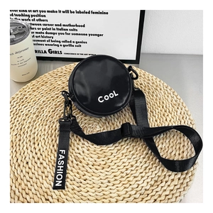 Close-up of black round crossbody bag with white Cool letter print and adjustable strap