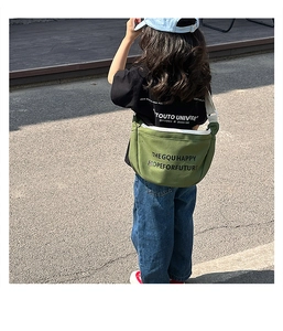 Détail du sac bandoulière en toile vert armée avec fermeture éclair blanche et texte