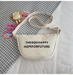 Gros plan du sac à bandoulière enfant en toile crème avec lettrage noir et sangle