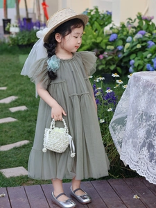 Détail d'une robe en tulle vert sauge pour fille avec sac en perles et chapeau de paille