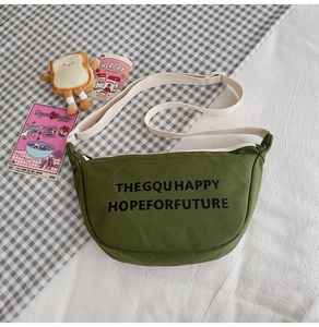 Vue détaillée du sac bandoulière en toile vert foncé avec imprimé lettres et sangle blanche