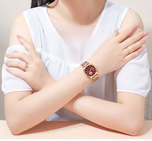 Close-up of a women's burgundy dial quartz watch with rose gold strap on a model wrist