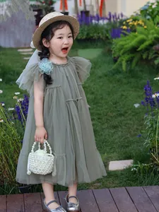Détail de la robe en tulle vert sauge avec épinglette florale et manches volantées fille