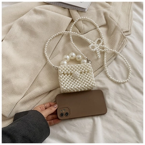 Detailed macro of handmade cream pearl mini bag showing fine weave and large bead handle