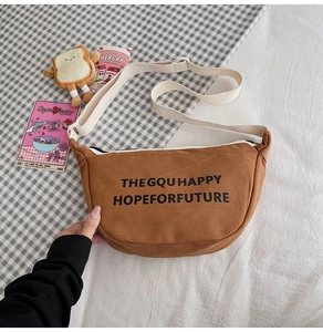 Détail d'un sac bandoulière en toile marron avec typographie et sangle réglable