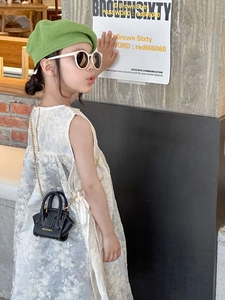 Détail d'un mini sac bandoulière noir avec chaîne dorée et coutures blanches sur un enfant