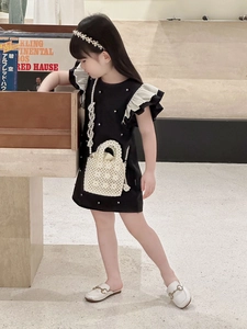 Detail of elegant black dress for girls with white frill sleeves and pearl embellishments