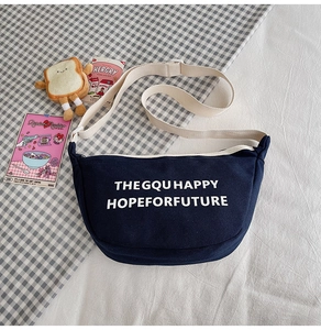 Détail du sac bandoulière en toile bleu marine avec sangle blanche et lettrage