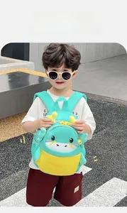 Detail view of a mint green cartoon dragon backpack with 3D yellow horns for toddlers