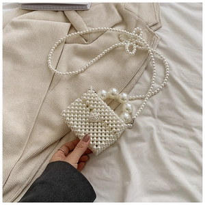 Detailed view of mini woven pearl crossbody bag with beaded handle and fine strap