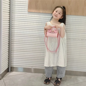 Mini sac bandoulière rose pour enfants avec poignée et boucles dorées porté par un enfant